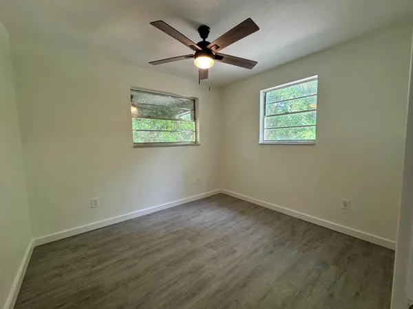 an empty room with wooden floor and ceiling fan