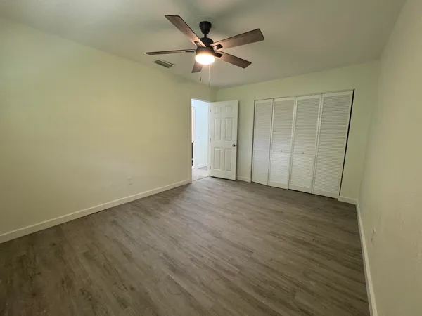 an empty room with wooden floor and ceiling fan