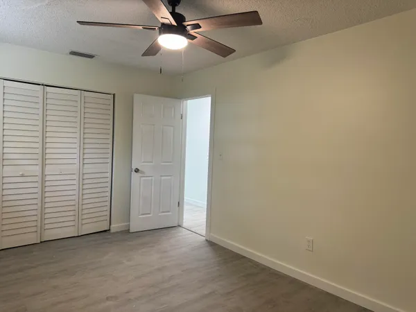 an empty room with closet and a ceiling fan