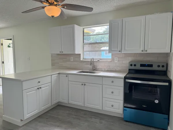 a kitchen with white cabinets appliances and a window