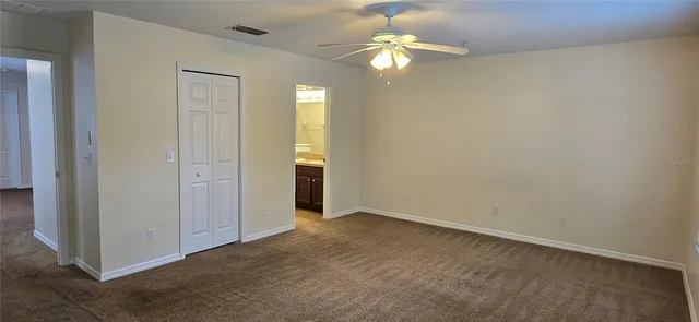 an empty room with a chandelier fan and a bathroom