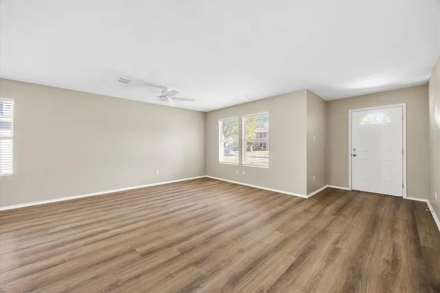 a view of an empty room with wooden floor and a window