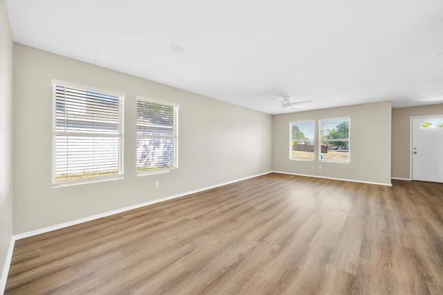 a view of an empty room with wooden floor and a window