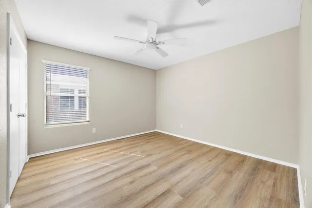 an empty room with a window and a ceiling fan