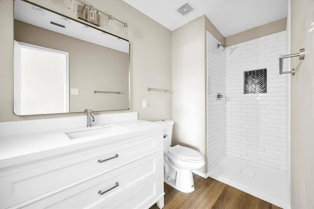 a bathroom with a granite countertop sink toilet a large mirror and shower