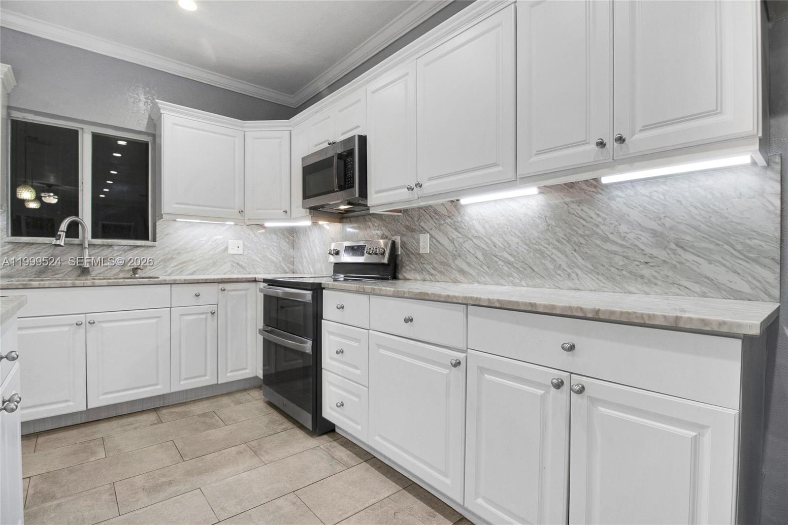 1925 Northwest 49th Street Miami, FL 33142 - Photo 11 of 30 a kitchen with white cabinets stainless steel appliances and sink