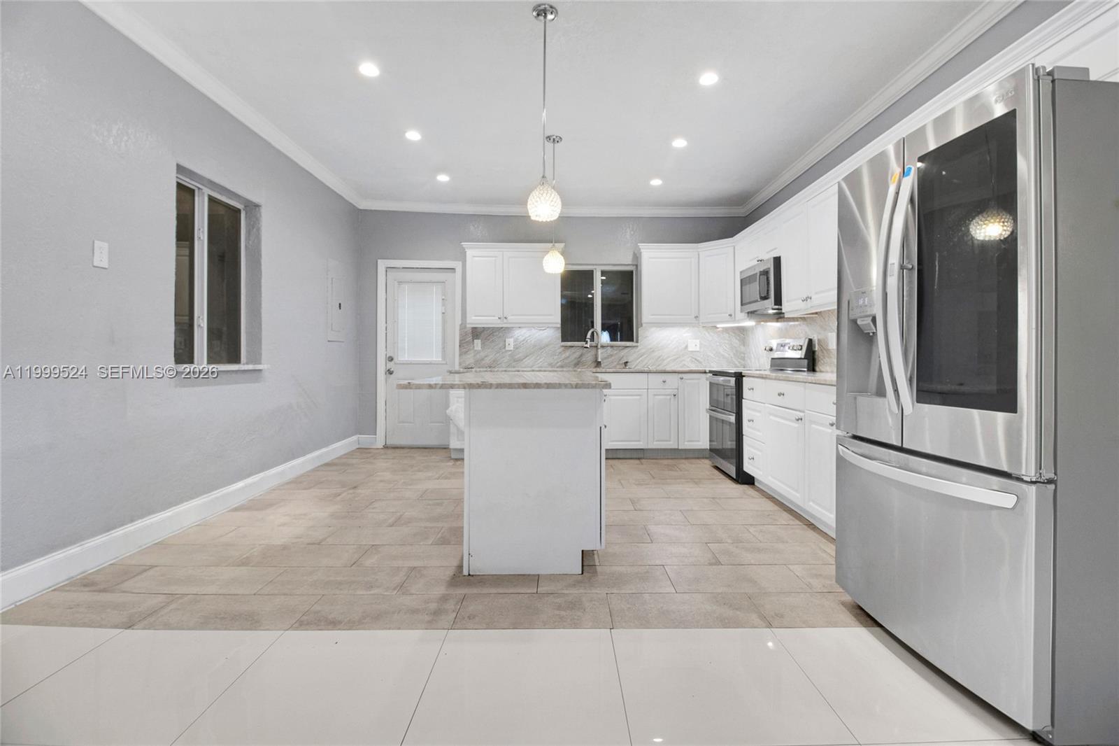 1925 Northwest 49th Street Miami, FL 33142 - Photo 10 of 30 a kitchen with kitchen island a sink stainless steel appliances and cabinets