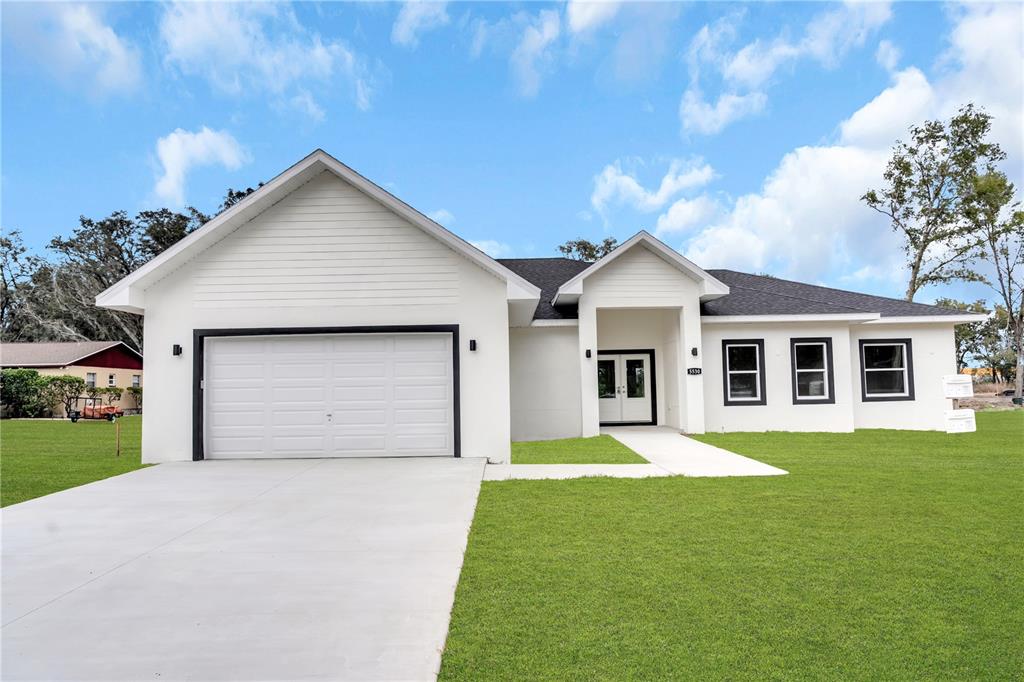 5530 Bell Street Zephyrhills, FL 33542 - Photo 2 of 16 a front view of a house with a yard and garage