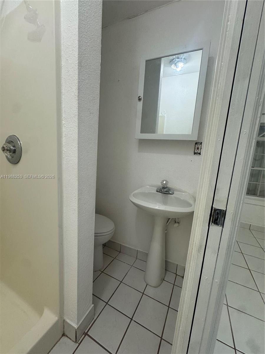4472 Southwest 9th Lane, Unit 1 Miami, FL 33134 - Photo 9 of 10 a bathroom with a sink a toilet and mirror