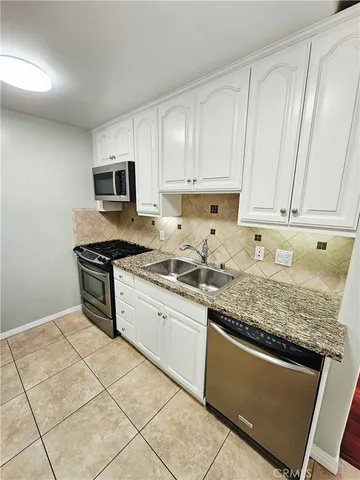 a kitchen with granite countertop a sink a stove and cabinets