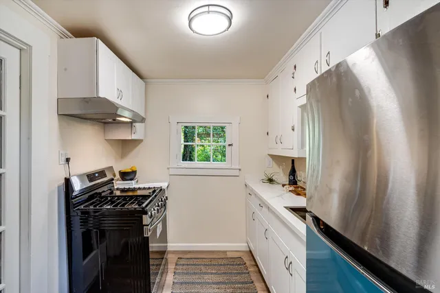 a kitchen with stainless steel appliances a stove a white cabinets and a window