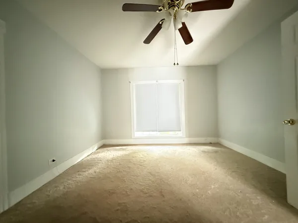 an empty room with a window and a fan