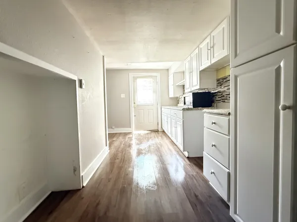 a kitchen with a refrigerator a stove top oven and wooden floor