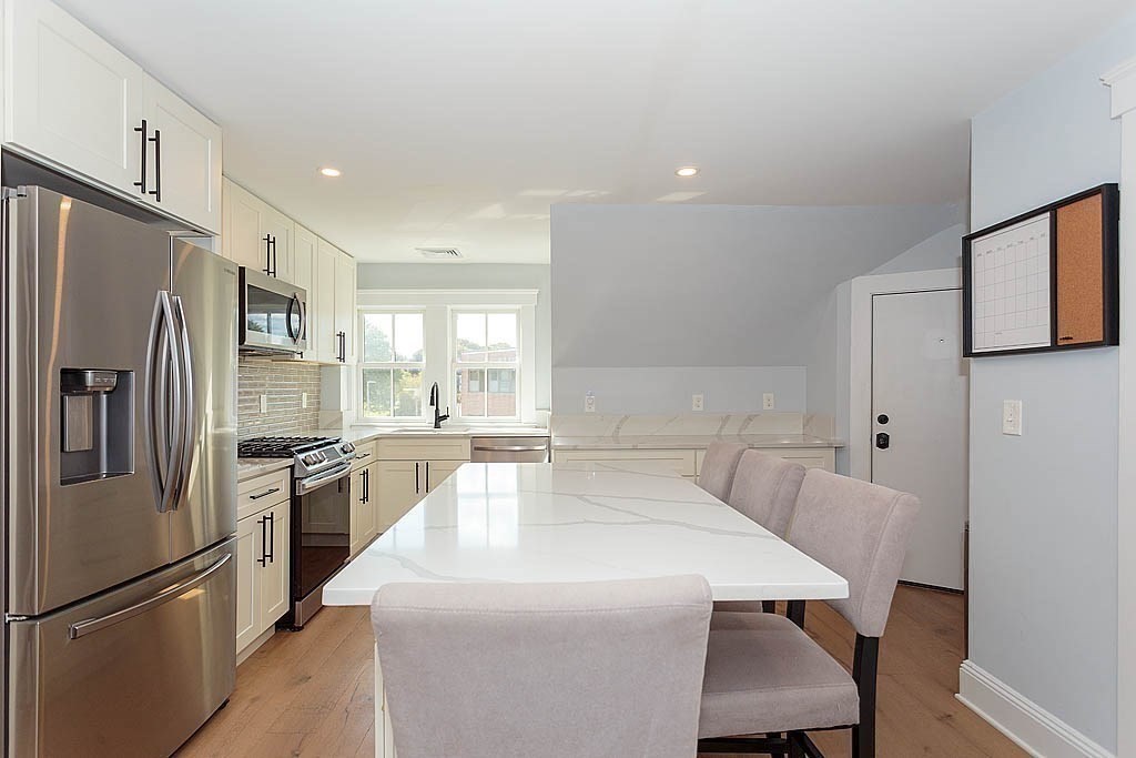 79 Robert Street, Unit 3 Boston, MA 02131 - Photo 3 of 20 a large kitchen with a table chairs refrigerator and microwave