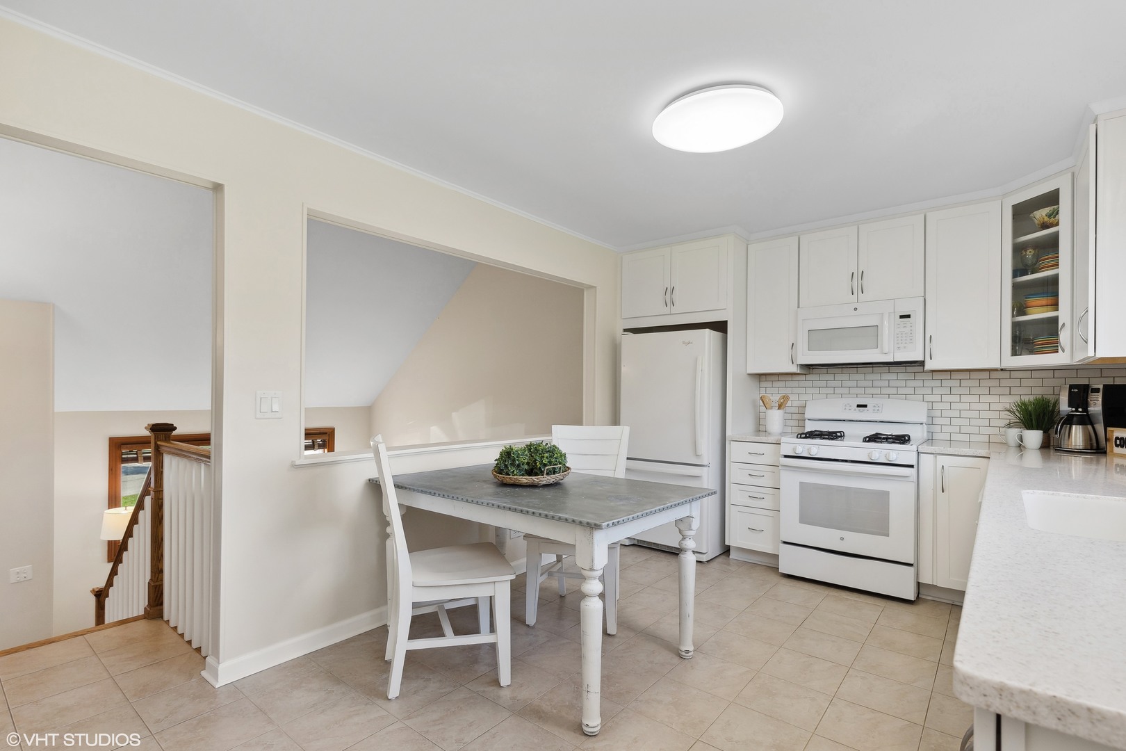 575 Forest View Road Lindenhurst, IL 60046 - Photo 6 of 21 a kitchen with a dining table chairs refrigerator and cabinets