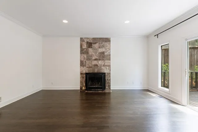 an empty room with wooden floor fireplace and windows