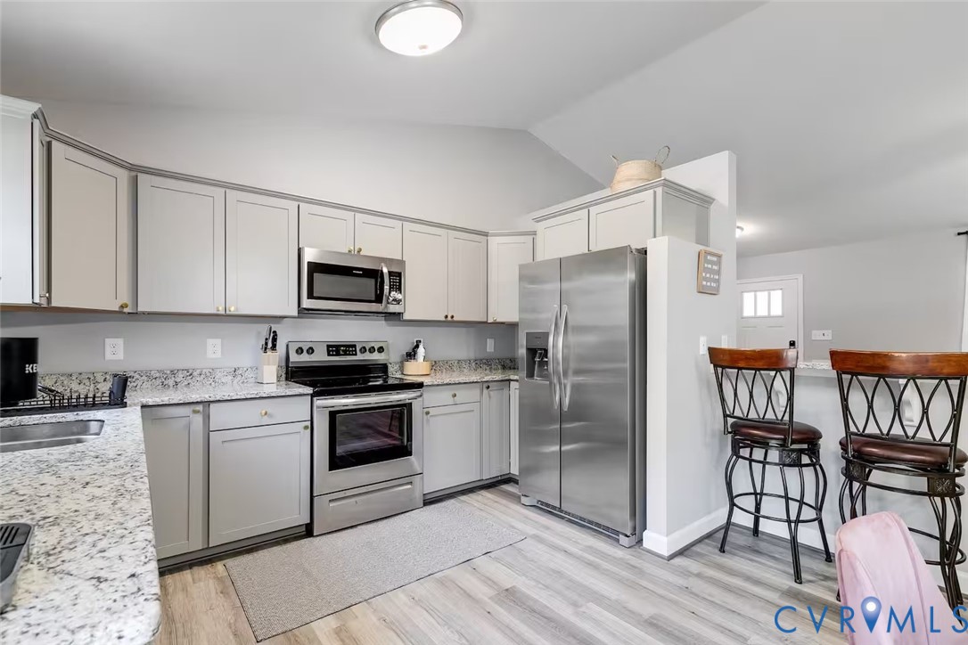 711 Jackson Street Colonial Beach, VA 22443 - Photo 20 of 41 a kitchen with stainless steel appliances granite countertop a stove a refrigerator a sink a dining table and chairs