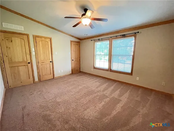 an empty room with chandelier fan and windows