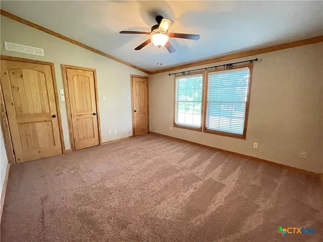an empty room with chandelier fan and windows