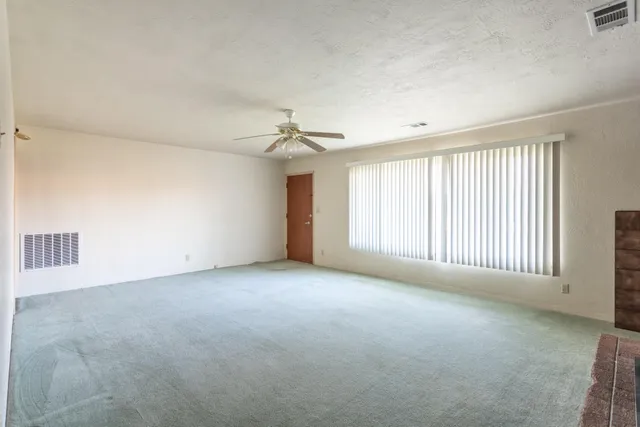 an empty room with windows and chandelier fan