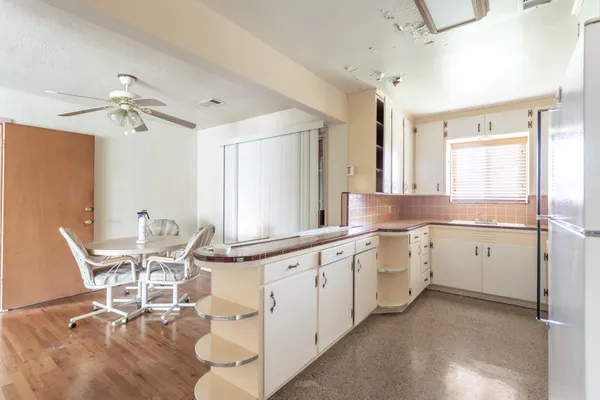a large white kitchen with granite countertop a stove a sink a dining table and chairs