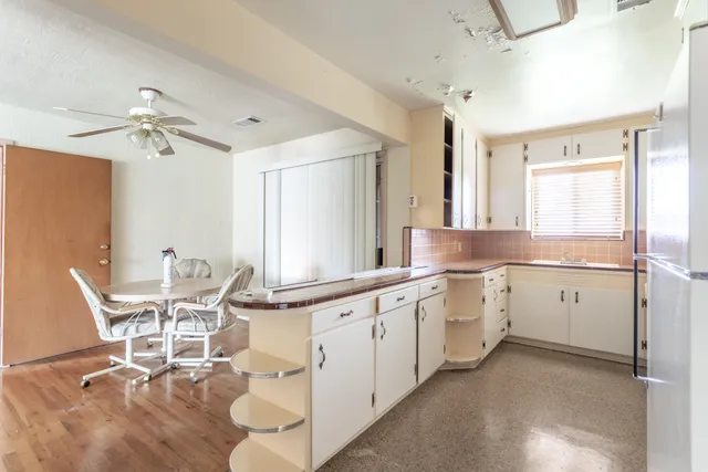 a large white kitchen with granite countertop a stove a sink a dining table and chairs