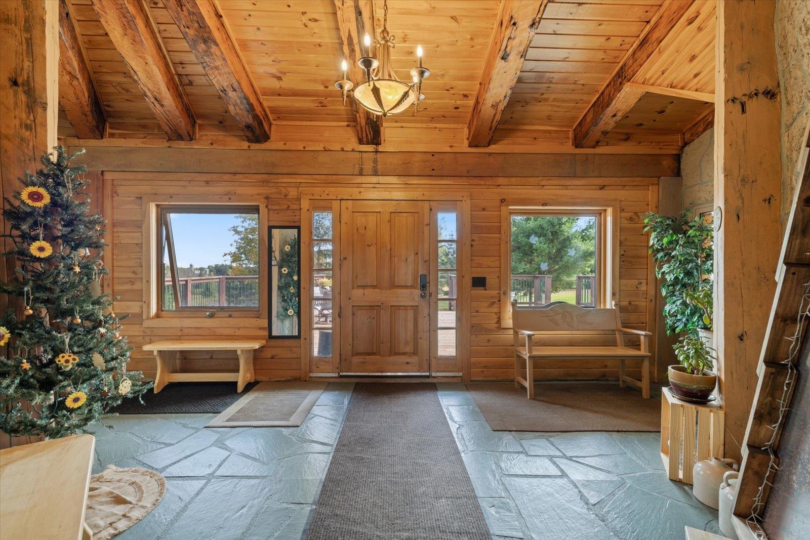 3581 County Line Road Sturgeon Lake, MN 55783 - Photo 26 of 85 Foyer entrance featuring wooden walls, a wood ceiling with exposed beams, and a chandelier