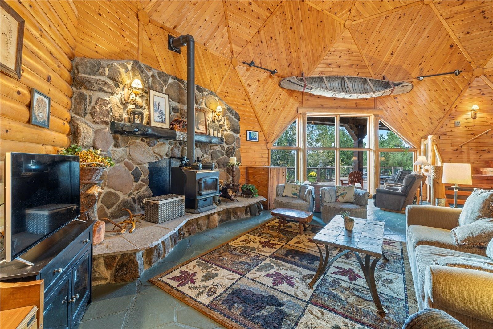 3581 County Line Road Sturgeon Lake, MN 55783 - Photo 32 of 85 Living area with a wood stove, wood ceiling, high vaulted ceiling, wooden walls, and stone tile flooring