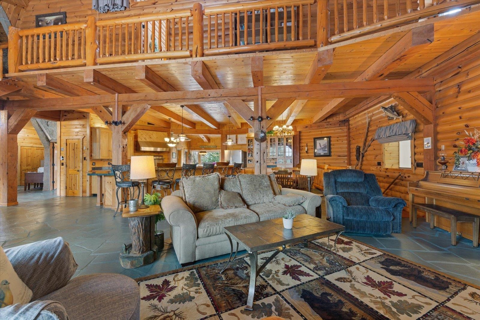 3581 County Line Road Sturgeon Lake, MN 55783 - Photo 34 of 85 Living area with wood walls, a wooden ceiling with exposed beams, a chandelier, healthy amount of natural light, and stone finish floors