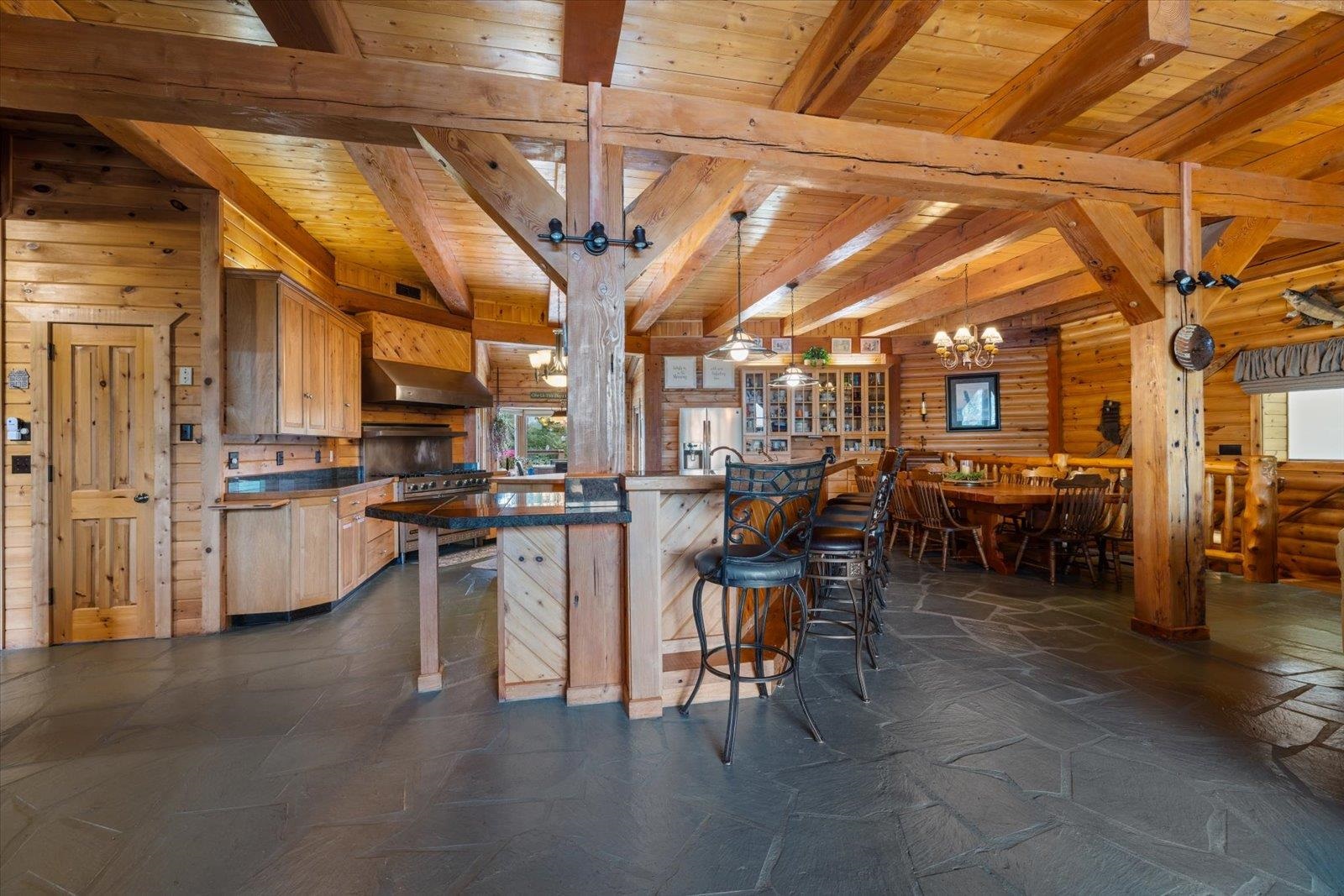 3581 County Line Road Sturgeon Lake, MN 55783 - Photo 38 of 85 Kitchen with pendant lighting, a breakfast bar area, a wooden ceiling with exposed beams, stone tile floors, and a chandelier