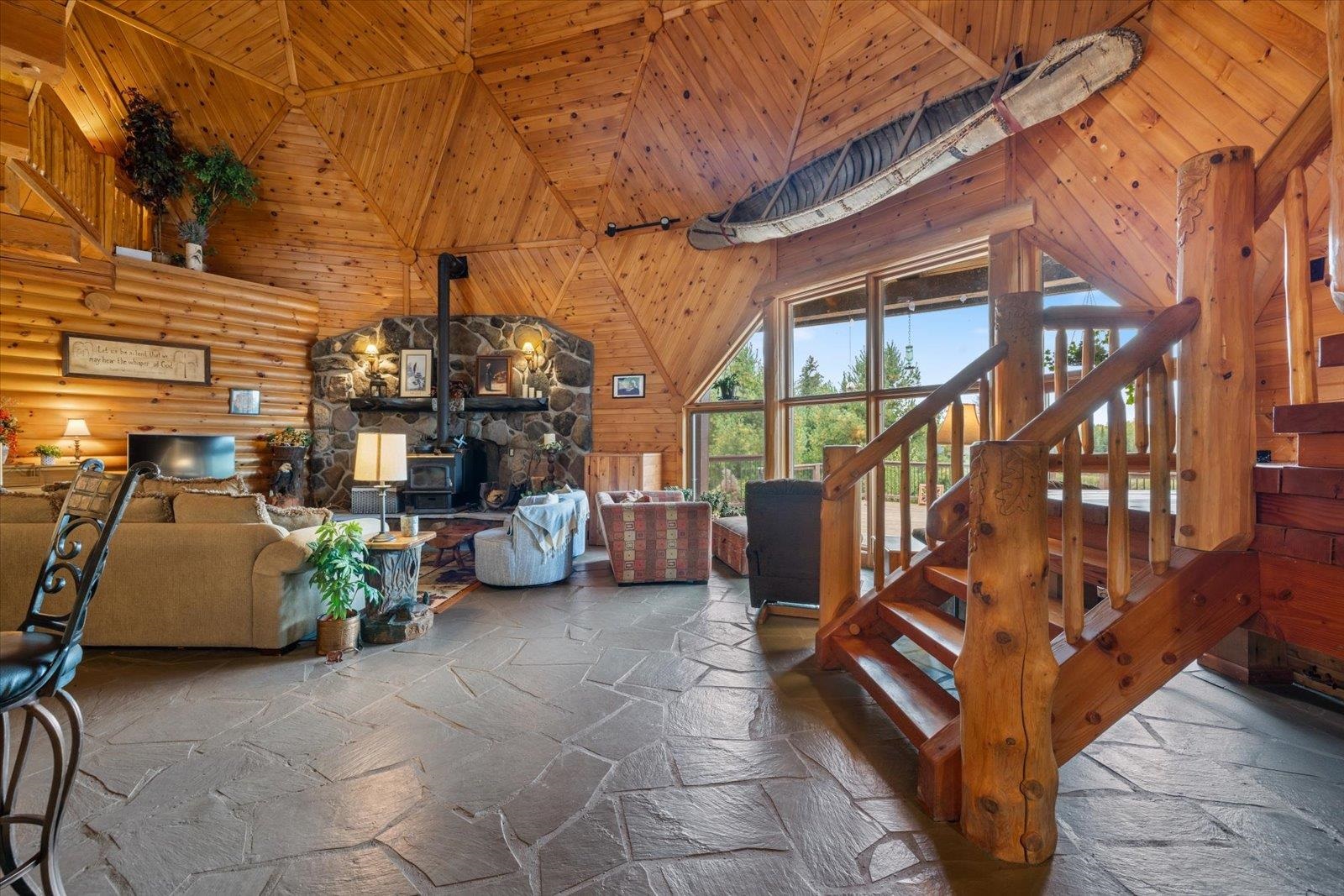 3581 County Line Road Sturgeon Lake, MN 55783 - Photo 40 of 85 Living room with a wood stove, high vaulted ceiling, stone tile floors, wood ceiling, and stairway