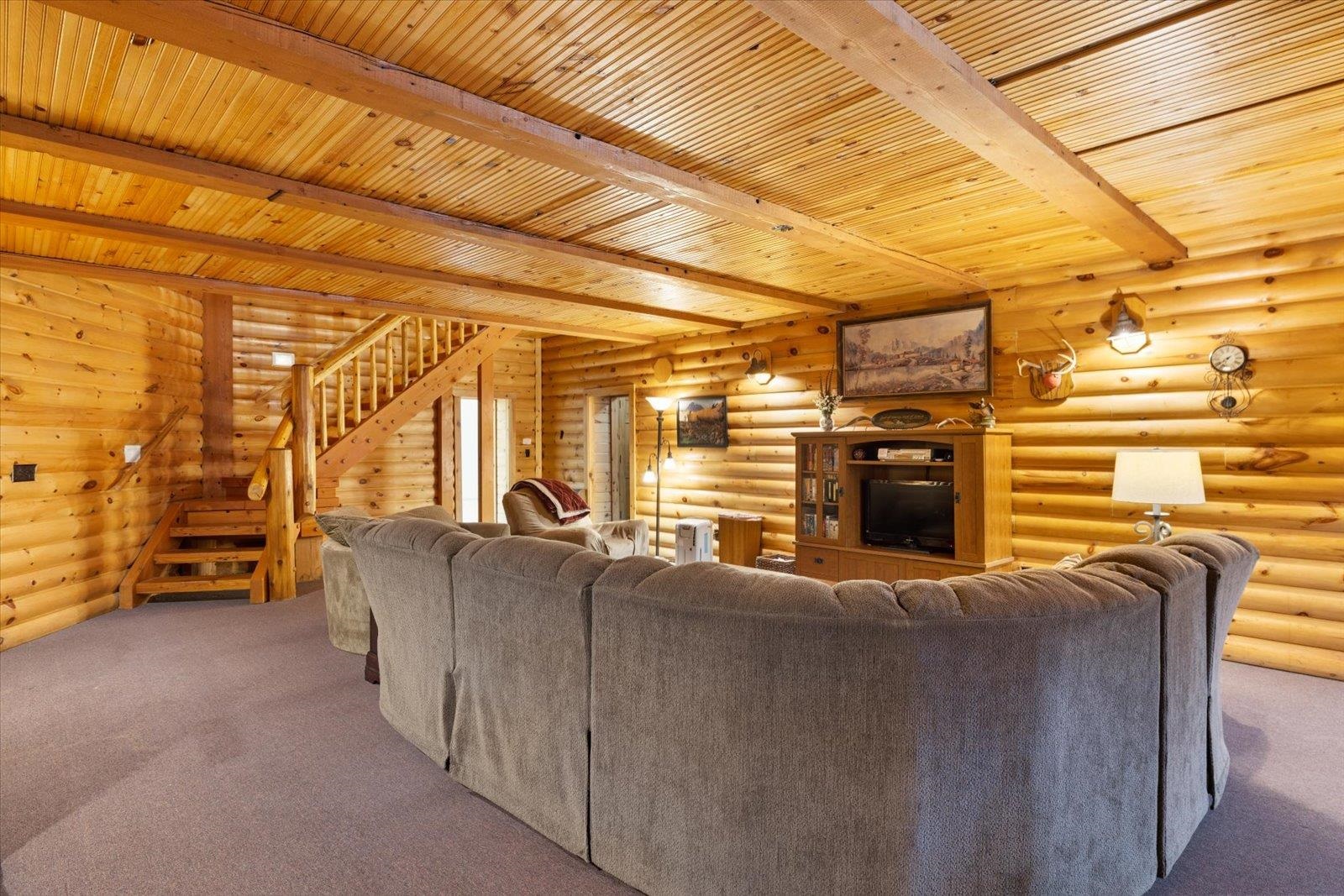 3581 County Line Road Sturgeon Lake, MN 55783 - Photo 48 of 85 Carpeted living room featuring rustic walls, stairs, and a wooden ceiling with exposed beams
