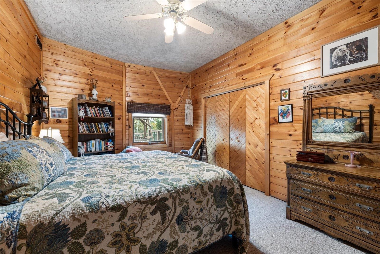 3581 County Line Road Sturgeon Lake, MN 55783 - Photo 57 of 85 Carpeted bedroom with wooden walls, a ceiling fan, a closet, and a textured ceiling