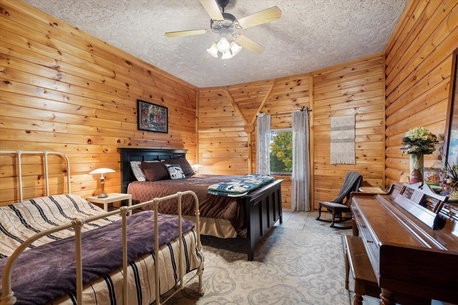 3581 County Line Road Sturgeon Lake, MN 55783 - Photo 59 of 85 Bedroom with wooden walls, a ceiling fan, and a textured ceiling