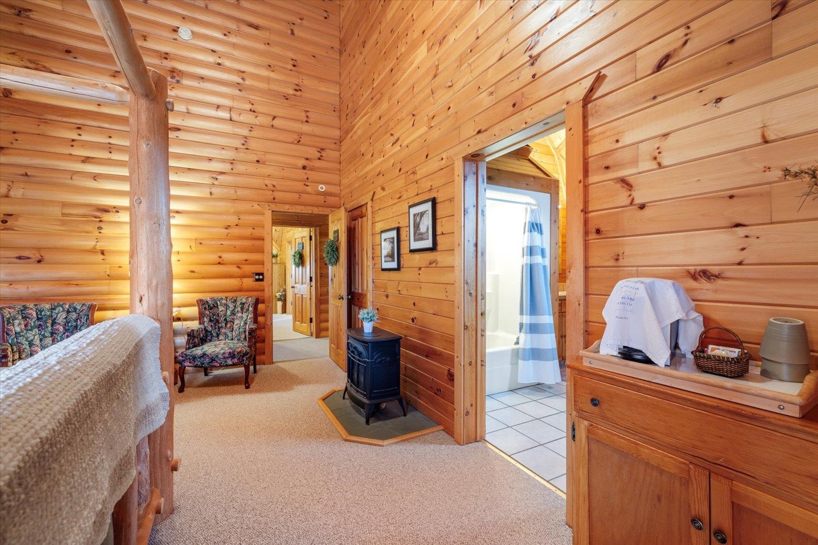 3581 County Line Road Sturgeon Lake, MN 55783 - Photo 65 of 85 Bedroom featuring a high ceiling, a wood stove, light colored carpet, and wood walls
