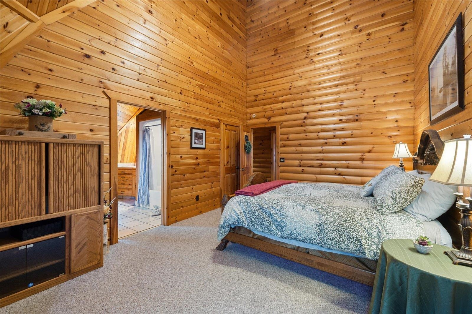 3581 County Line Road Sturgeon Lake, MN 55783 - Photo 66 of 85 Carpeted bedroom featuring a high ceiling, wood walls, and ensuite bathroom