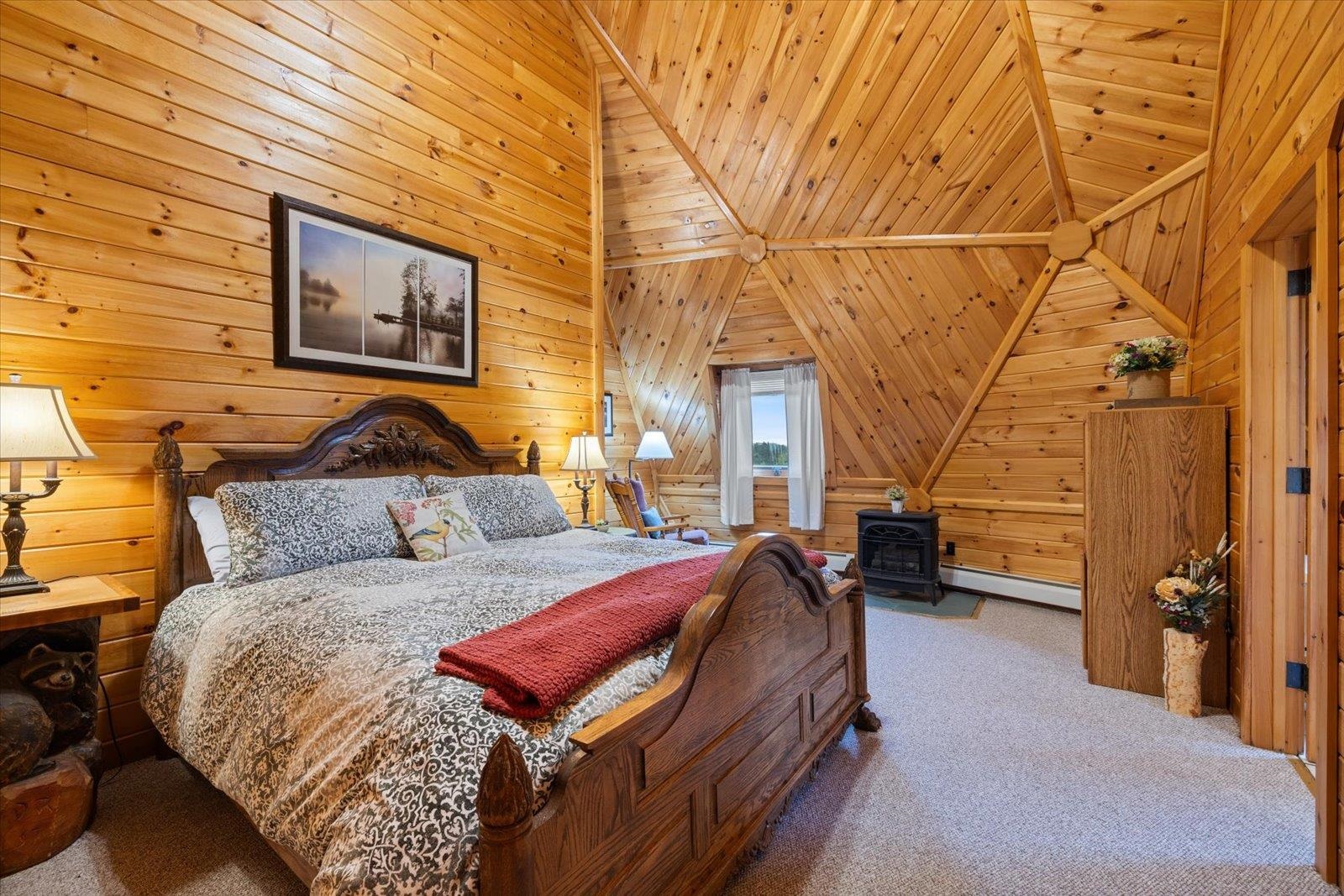 3581 County Line Road Sturgeon Lake, MN 55783 - Photo 67 of 85 Bedroom featuring wooden walls, carpet floors, a baseboard radiator, a wood stove, and wooden ceiling