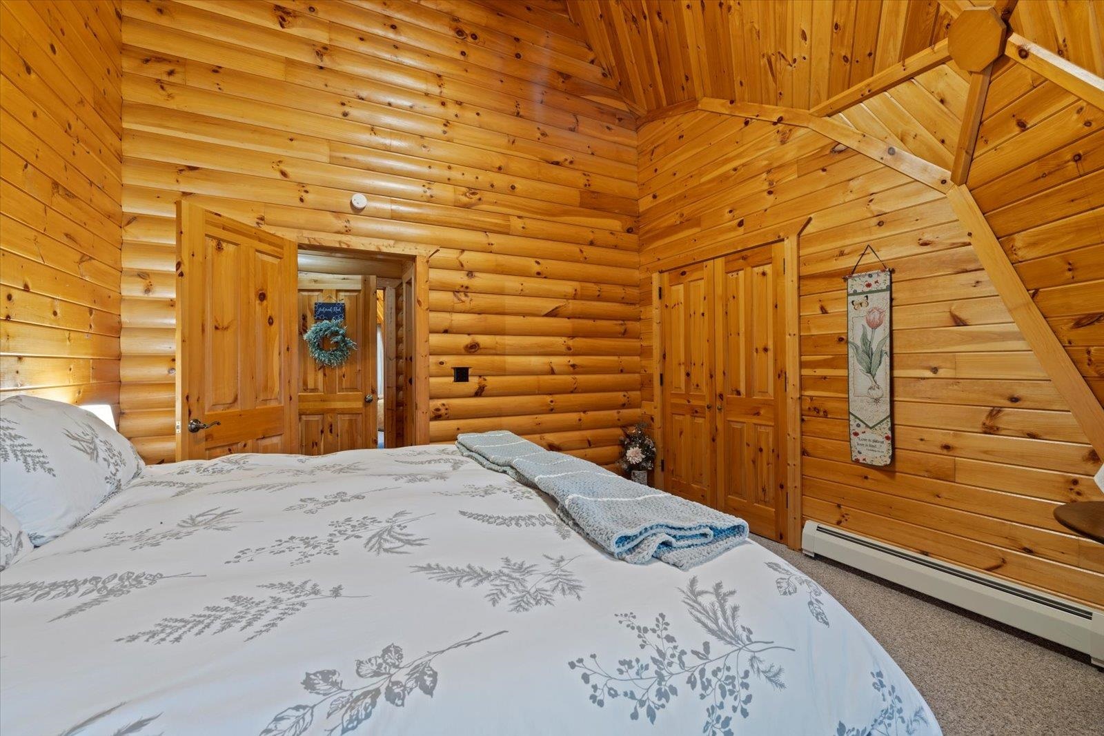 3581 County Line Road Sturgeon Lake, MN 55783 - Photo 69 of 85 Carpeted bedroom featuring baseboard heating, rustic walls, a closet, and a towering ceiling