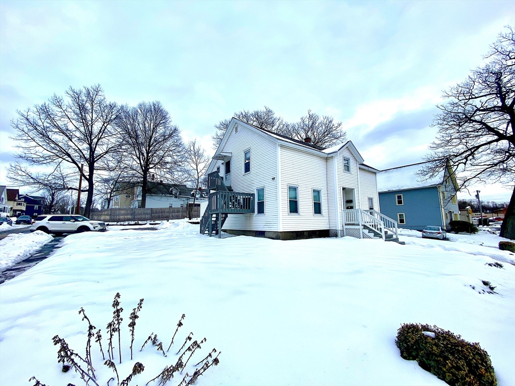 82 Mill Street Worcester, MA 01603 - Photo 3 of 39 a view of a white house with a yard covered in snow
