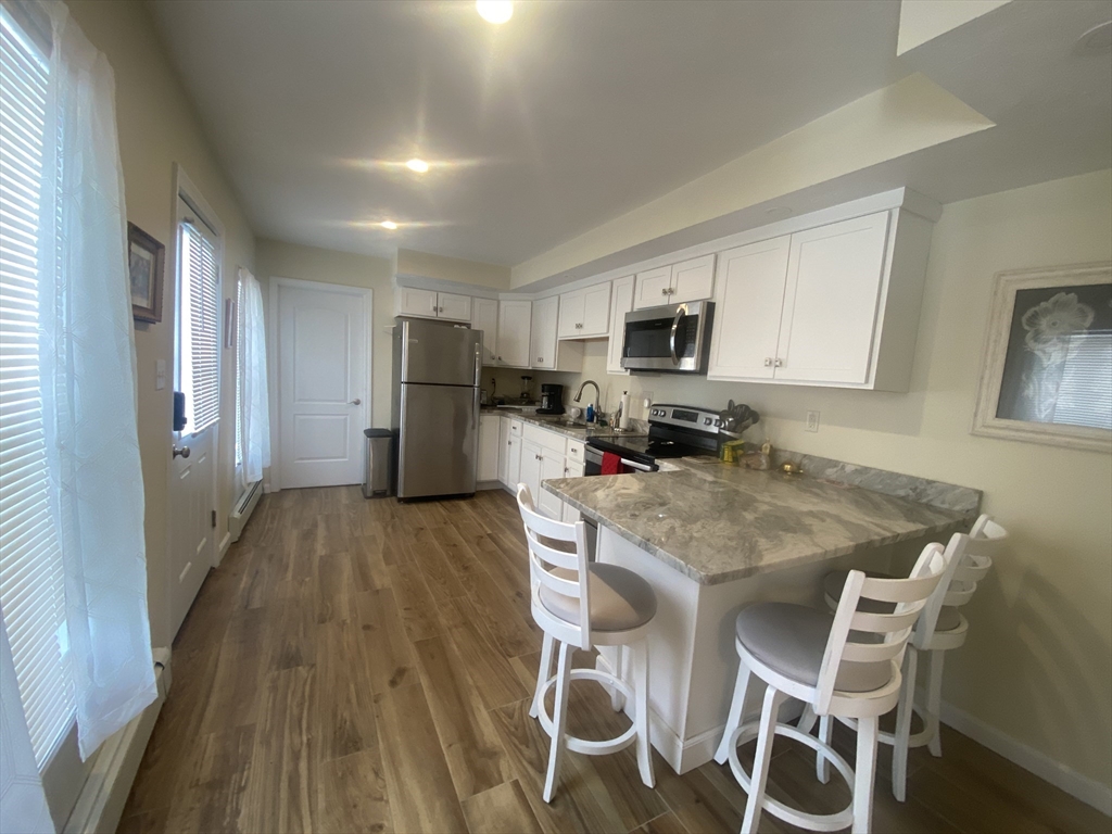 82 Mill Street Worcester, MA 01603 - Photo 8 of 39 a kitchen with a table chairs refrigerator and microwave