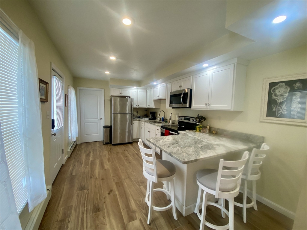 82 Mill Street Worcester, MA 01603 - Photo 10 of 39 a kitchen with stainless steel appliances granite countertop a refrigerator a stove top oven a sink dishwasher and white cabinets with wooden floor
