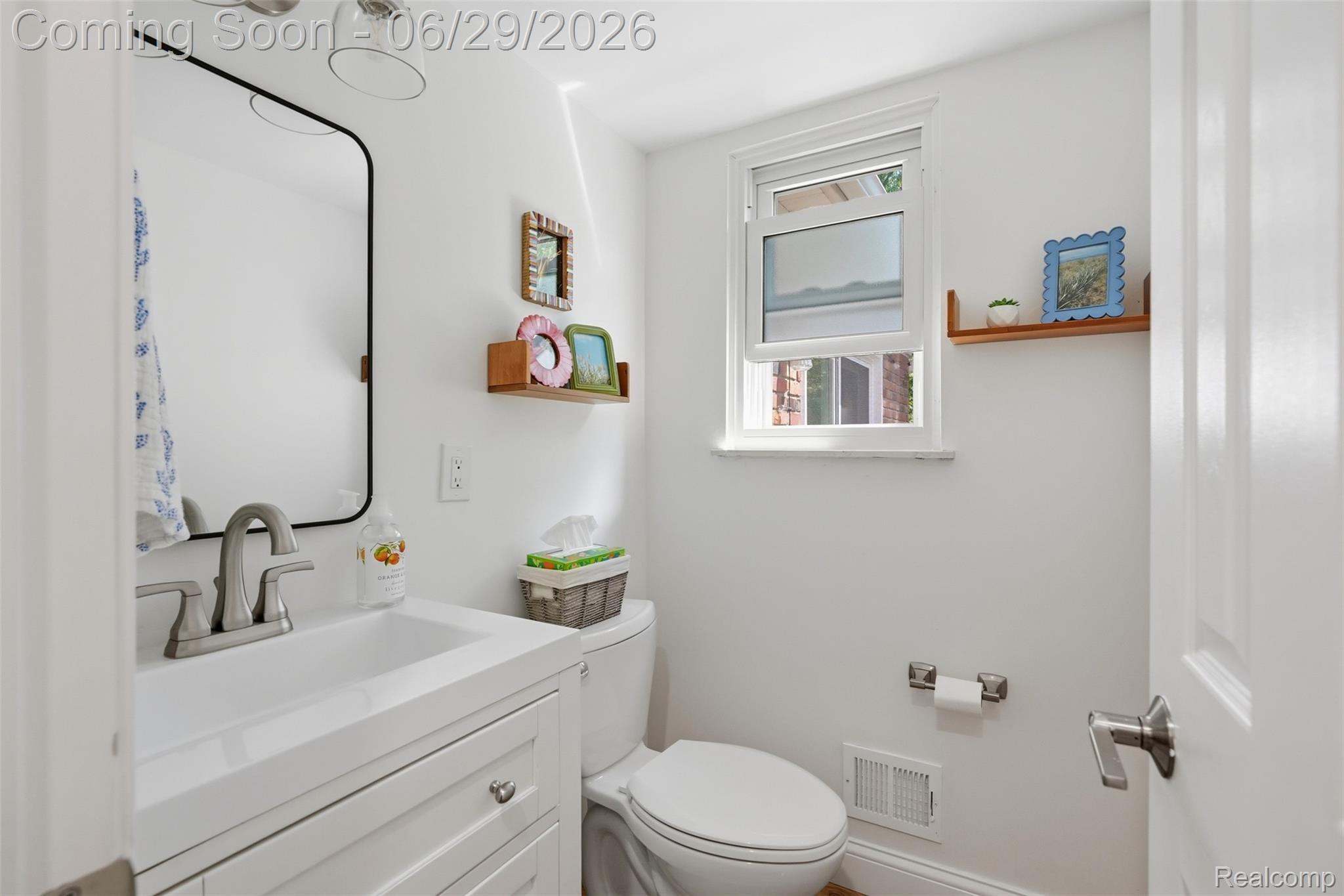 45179 Rudgate Road Canton, MI 48188 - Photo 15 of 48 Bright white bathroom featuring a contemporary vanity with an integrated sink, a sleek black-framed mirror, and a window for natural light