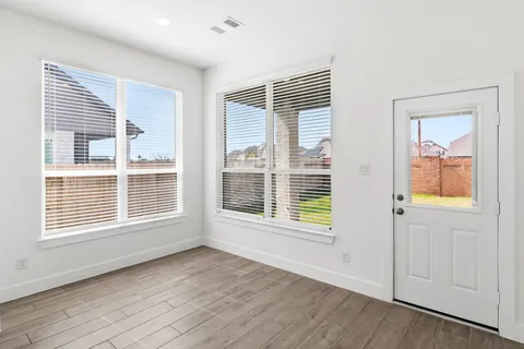a view of an empty room with a window and wooden floor