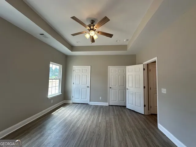 a view of empty room with wooden floor and fan