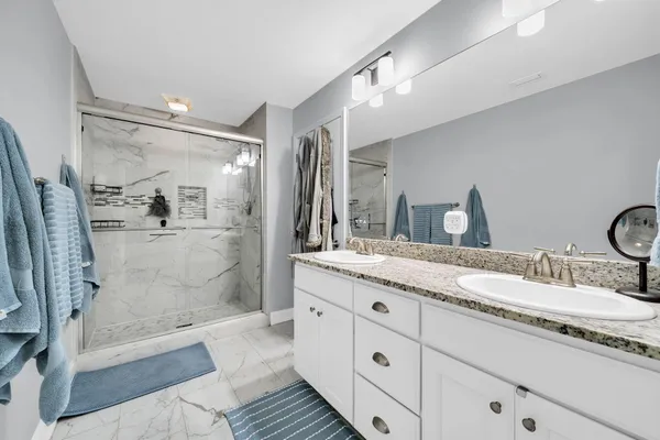 a bathroom with a granite countertop sink mirror and shower