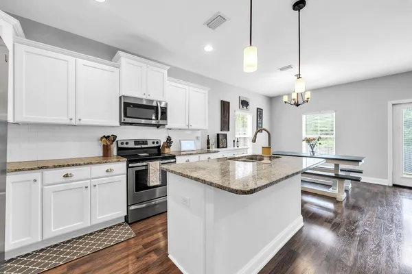 a kitchen with kitchen island granite countertop a sink a counter top space appliances and cabinets