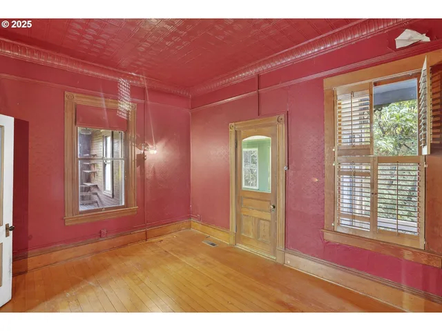 a view of an empty room with wooden floor and windows