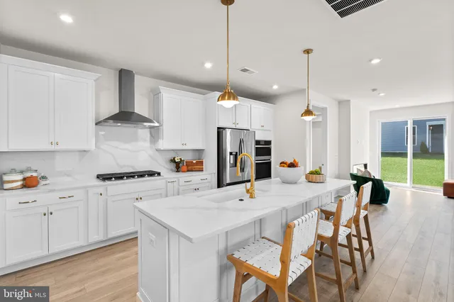 a kitchen with stainless steel appliances kitchen island granite countertop a stove a refrigerator a sink a dining table and chairs with wooden floor