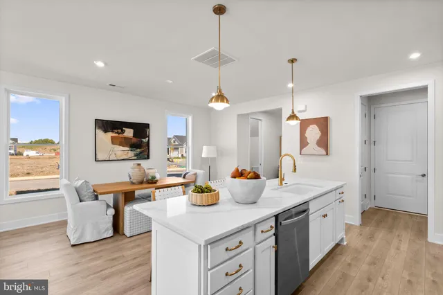 a open kitchen with stainless steel appliances granite countertop a sink dishwasher a dining table and chairs with wooden floor