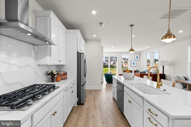 a kitchen with stainless steel appliances a sink a stove a refrigerator cabinets and living room view